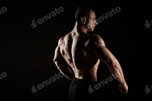 Preview: torso of attractive male body builder on black background.