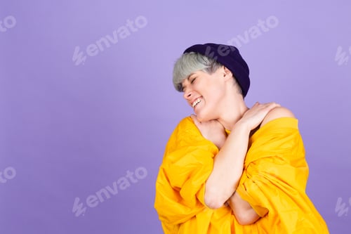 Preview: Stylish european woman on purple background self care hugging herself with smile and closed eyes