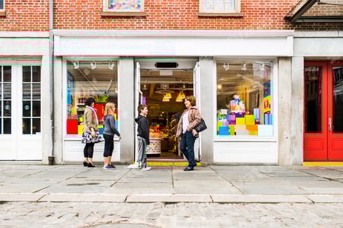 Preview: Side view of people standing on sidewalk outside candy shop in city