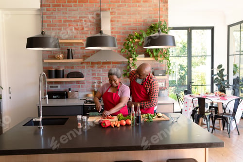 Preview: Happy african american senior couple cooking together in kitchen
