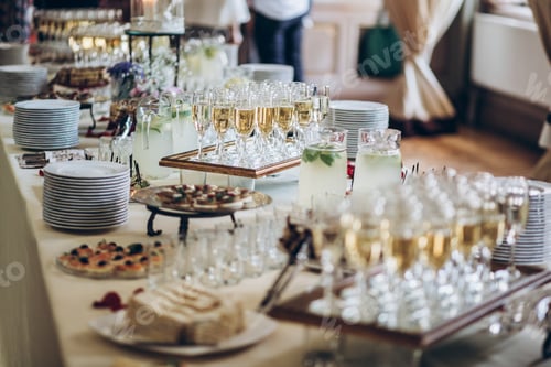 Preview: Stylish champagne glasses and food appetizers on table at wedding reception