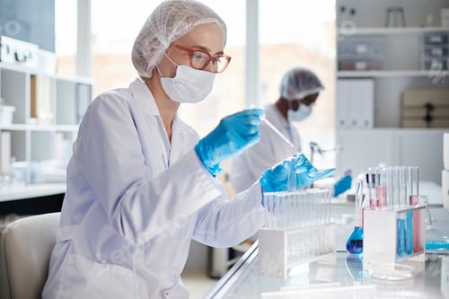 Preview: Female Chemist in Mask Dripping Liquid into Test Tube during Experiment in Laboratory