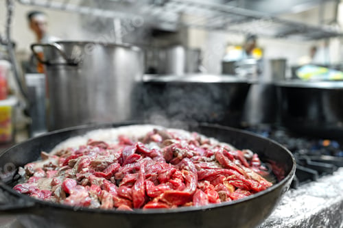 Preview: Meat fryed on frying pan on modern stove in professional kitchen
