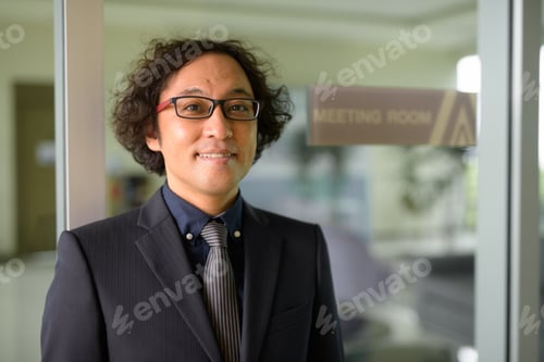 Preview: Happy Japanese businessman with curly hair smiling at the meeting room