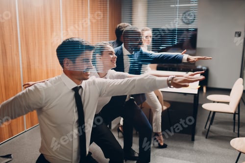 Preview: Businessman and businesswoman team doing warm up and yoga exercises before office meeting.
