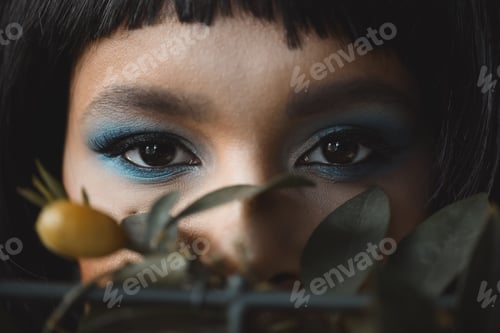 Preview: selective focus of woman with bright makeup looking at camera