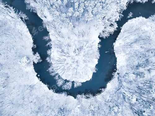 Preview: Aerial view of river flowing in snow-covered forest in winter.