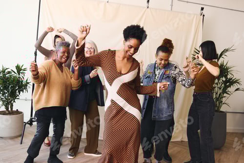 Preview: International Women's Day portrait of multiethnic mixed age range women dancing and smiling together