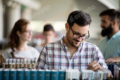 Preview: Male student picking a book in a library