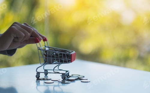 Preview: Hands holding a small shopping cart full of coins for saving money and financial concept