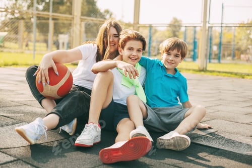 Preview: Portrait of teenagers sitting on a basketball court. Children relax after the game, talk and laugh.