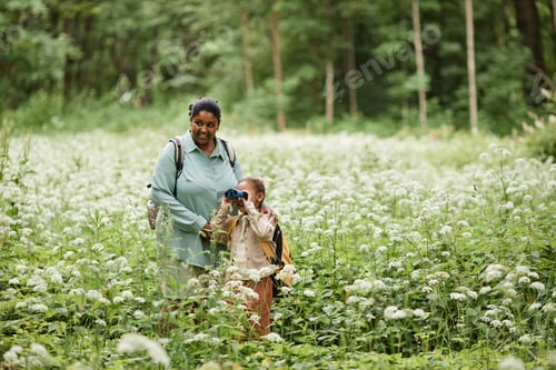 Preview: Black mother and daughter hiking and looking in binoculars