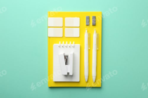 Preview: Stapler and other stationery on turquoise background, top view