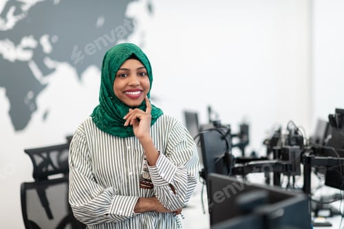 Preview: Portrait of muslim black female software developer with green hijab standing at modern open plan