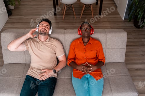 Preview: Two people relaxing on a couch while listening to music at home in the afternoon