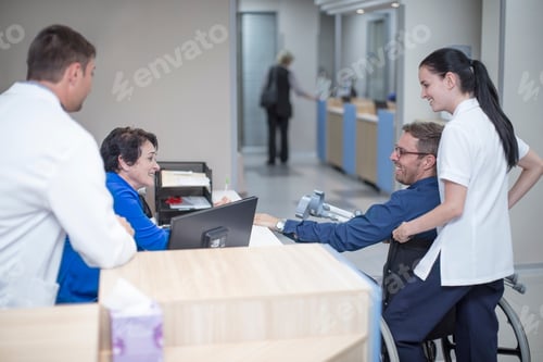 Preview: Patient siting in wheel chair talking to staff at the reception