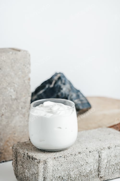 Preview: Yogurt or sour cream in glass on white with rocks background