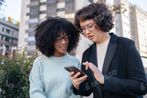 Preview: Two friends looking at smartphone in the street