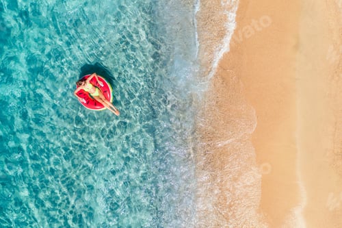 Preview: Aerial view of a young woman swimming with red swim ring