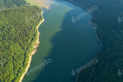 Preview: Top down aerial view of big lake with clear blue water between high mountain hills