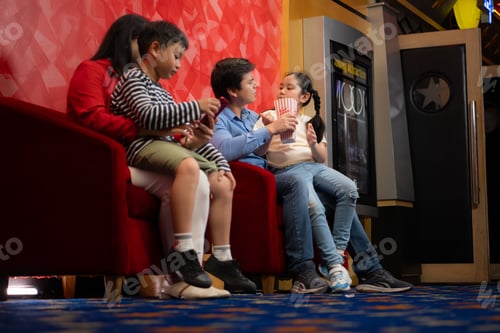 Preview: Parents and children sit and eat popcorn while waiting to see a movie in the cinema