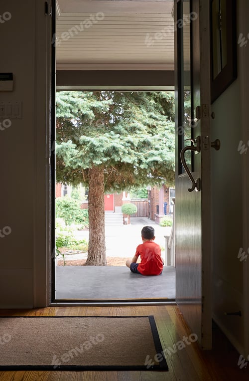 Preview: Young boy sitting on front step of house, rear view