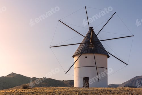 Preview: Old windmill in the field with hills and mountains in the background