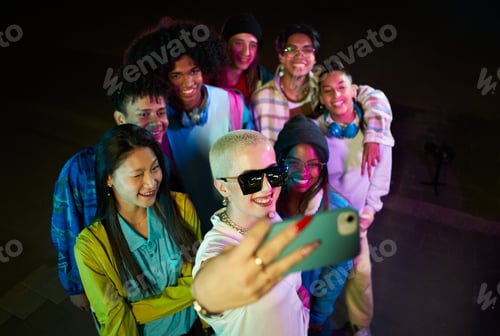 Preview: Group of friends taking selfie with mobile phone having fun at the party at night