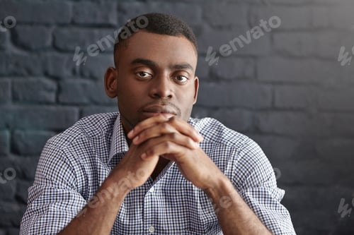 Preview: Portrait of handsome young dark-skinned male in formal wear looking at camera with pensive thoughtfu