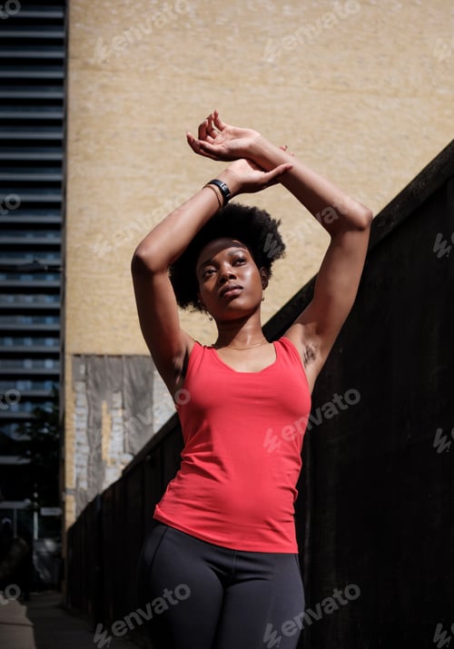 Preview: Young black woman stretching in a street of London.