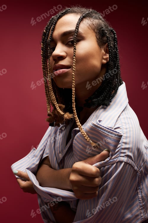 Preview: Confident young African American woman with braids poses in a vibrant studio