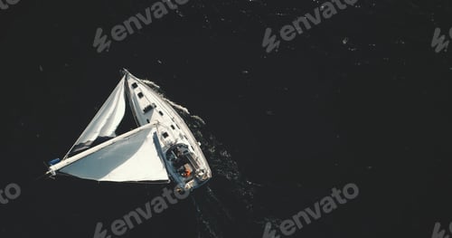 Preview: Top down of white sailing yacht on black water of ocean bay aerial. Nobody nature seascape at summer