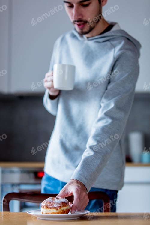 Preview: Young man take a donut on a table