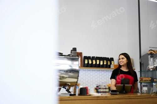 Preview: Smiling 20s caucasian woman cashier at coffee shop near blank copy space area