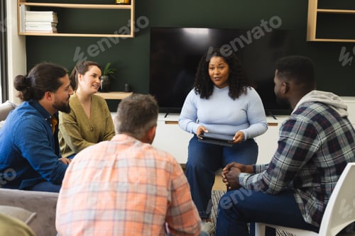 Preview: Diverse group of friends and female therapist with tablet in group therapy session