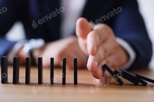 Preview: Risk. Man stopping domino effect at table, closeup