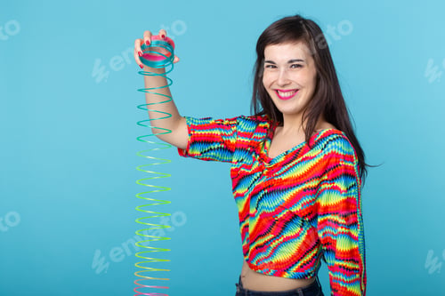 Preview: young woman playing with a slinky on blue background