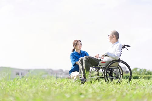 Preview: Smiling Woman with Senior Man in Wheelchair Outdoors