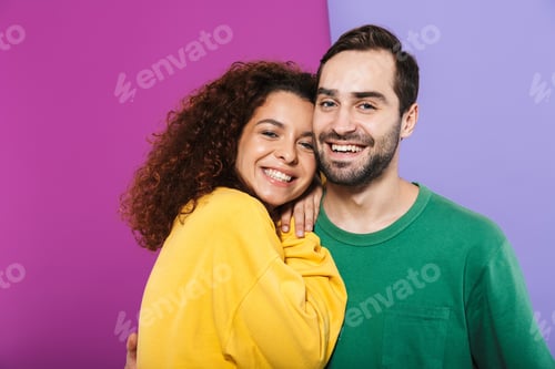 Preview: Portrait of brunette young couple man and woman in colorful clothing smiling and hugging together