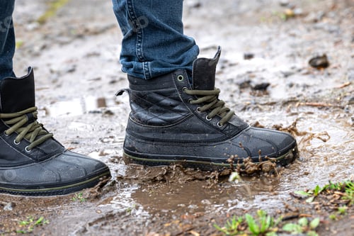 Preview: A man in jeans and boots walks through the swamp in rainy weather.