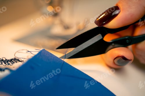 Preview: close-up in a sewing workshop scissors for working on fabric cut off blue thread