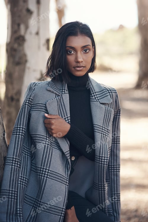 Preview: Its coat season. Shot of a fashionable young woman posing against a nature background.