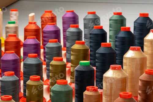 Preview: Row of multicolored thread spools at sewing factory