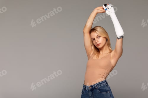 Preview: Studio portrait of beautiful young blonde girl with disability wearing sensory bionic prosthetic arm