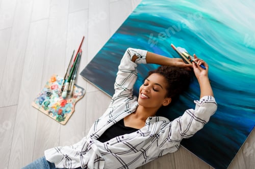 Preview: Top view of happy painter woman lying on canvas