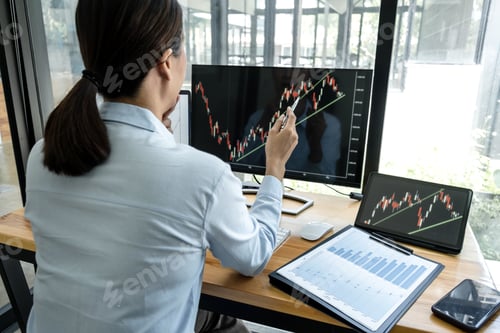 Preview: Businesswoman investor having planning a new project and analyzing graph data with display screen