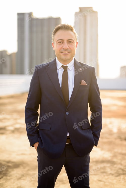Preview: Happy mature handsome businessman in suit against view of the city