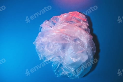 Preview: Transparent plastic bag on blue background. Minimal style, flat lay, top view, copy space.