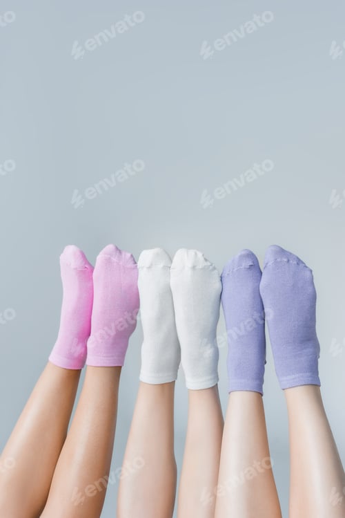 Preview: partial view of female legs in different colorful socks isolated on gray background