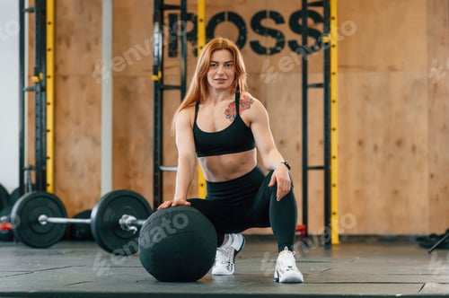 Preview: Front view. Sitting, barbell on the floor. Beautiful strong woman is in the gym